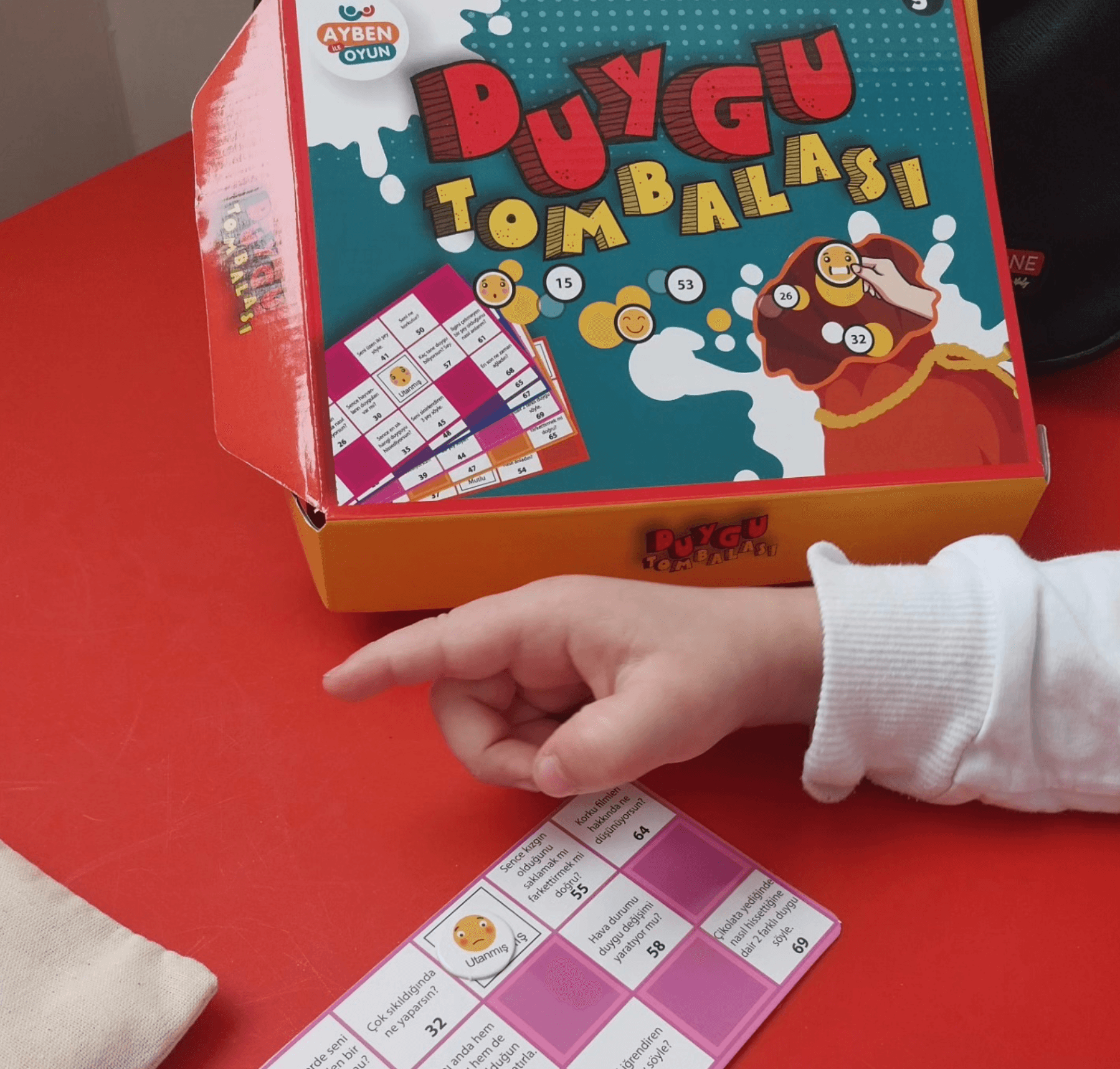 Duygu kartları ve duygu tombalası materyalleri; yalnızca bir el görünüyor.